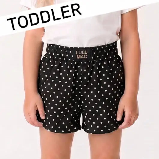 Toddler girl wearing Lulu Mac black mini polka dot boutique shorts for summer.
