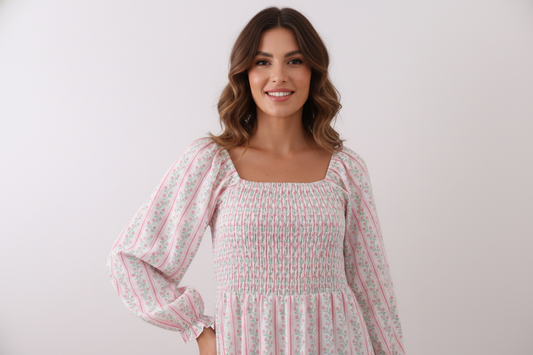 Woman wearing a white dress with floral patterns against a plain background